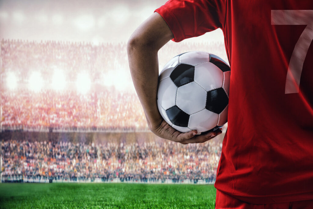 soccer football player in red shirt holding ball in the stadium