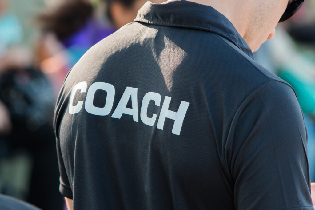 back of a black color shirt with the word Coach written on