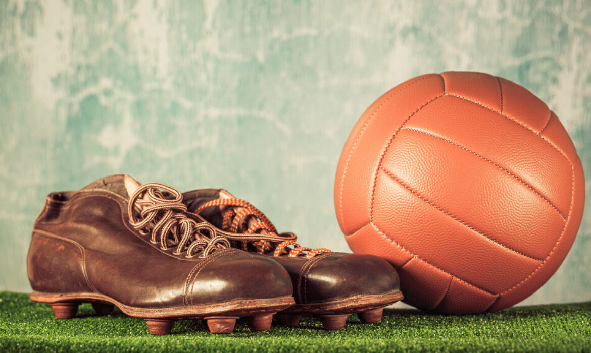 Retro outdated soccer spike boots and football. Vintage old style filtered photo