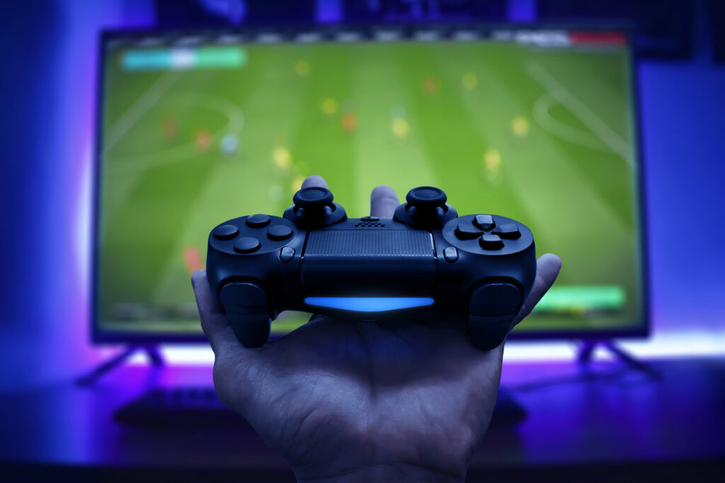 Controller with blurred football game on TV screen