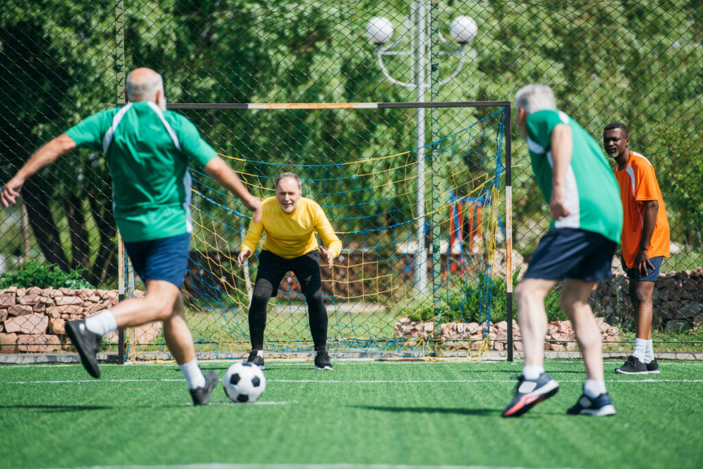 elderly friends playing football together