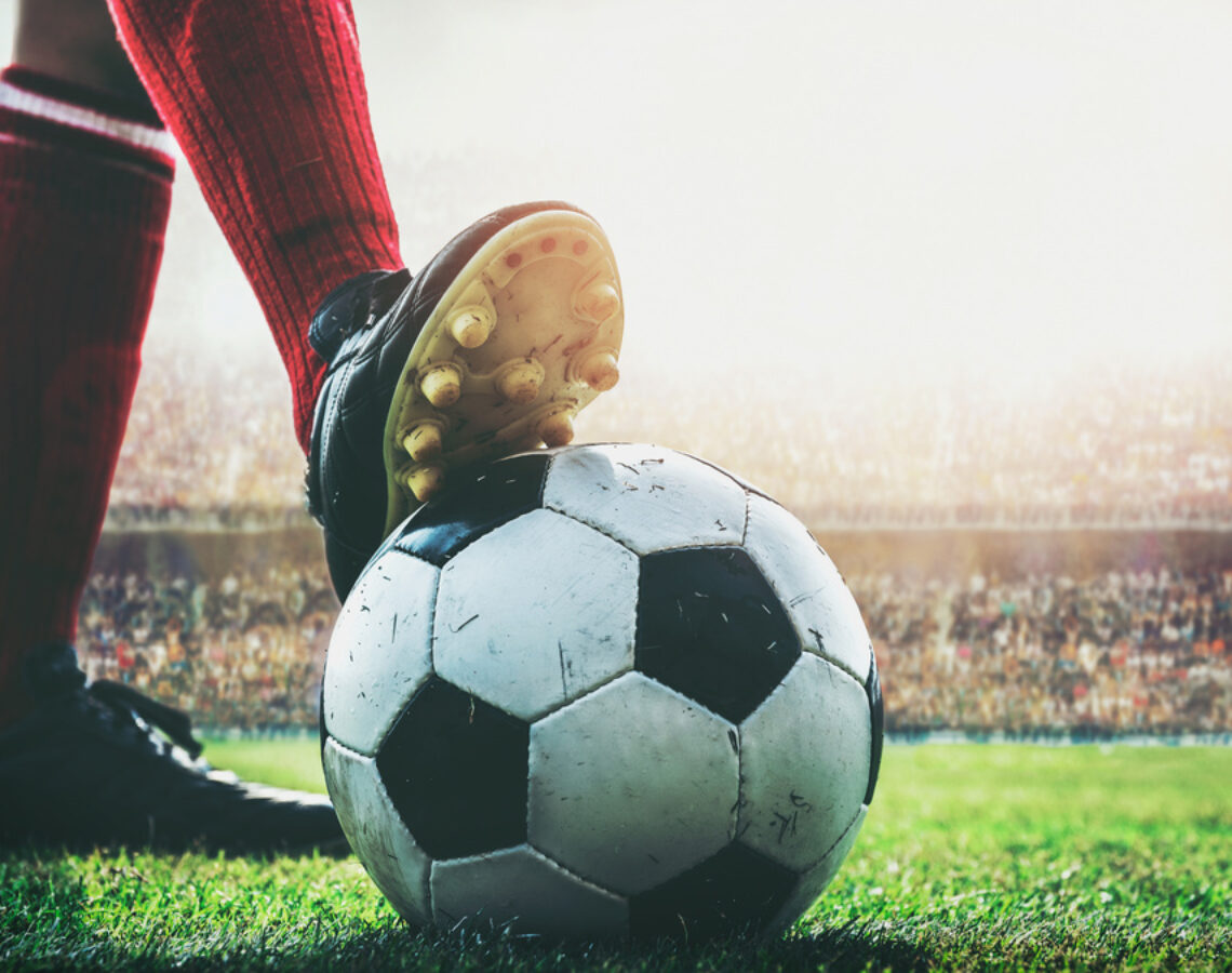 feet of football player on soccer ball in the stadium