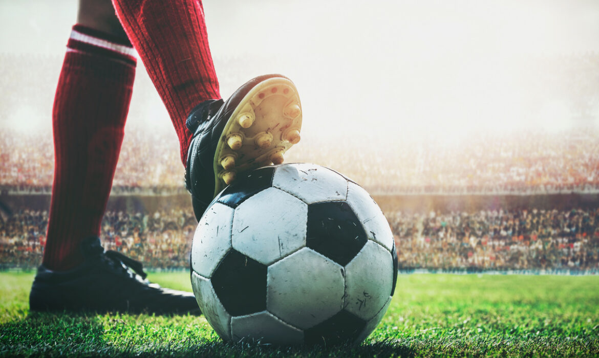 feet of football player on soccer ball in the stadium