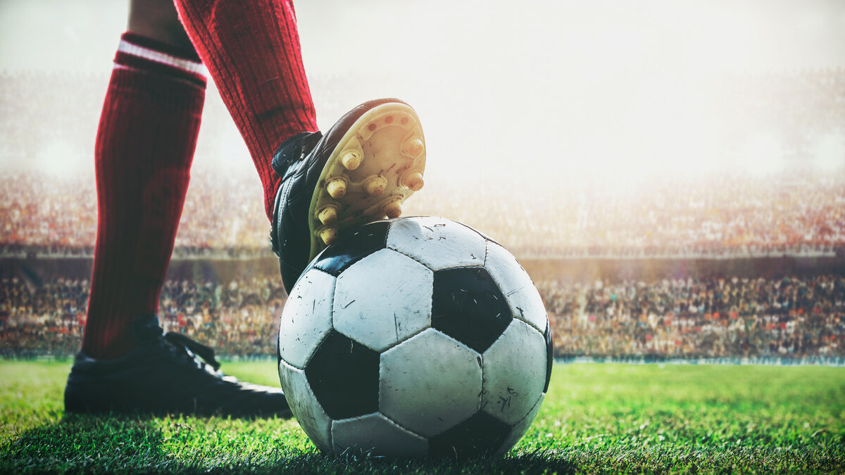 feet of football player on soccer ball in the stadium