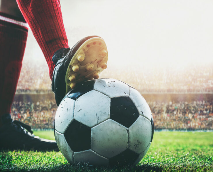 feet of football player on soccer ball in the stadium