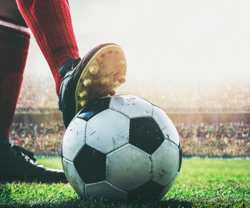 feet of football player on soccer ball in the stadium