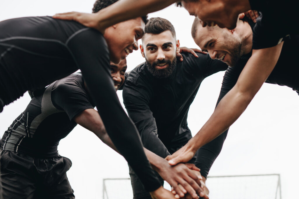 Soccer players joining hands standing in a huddle