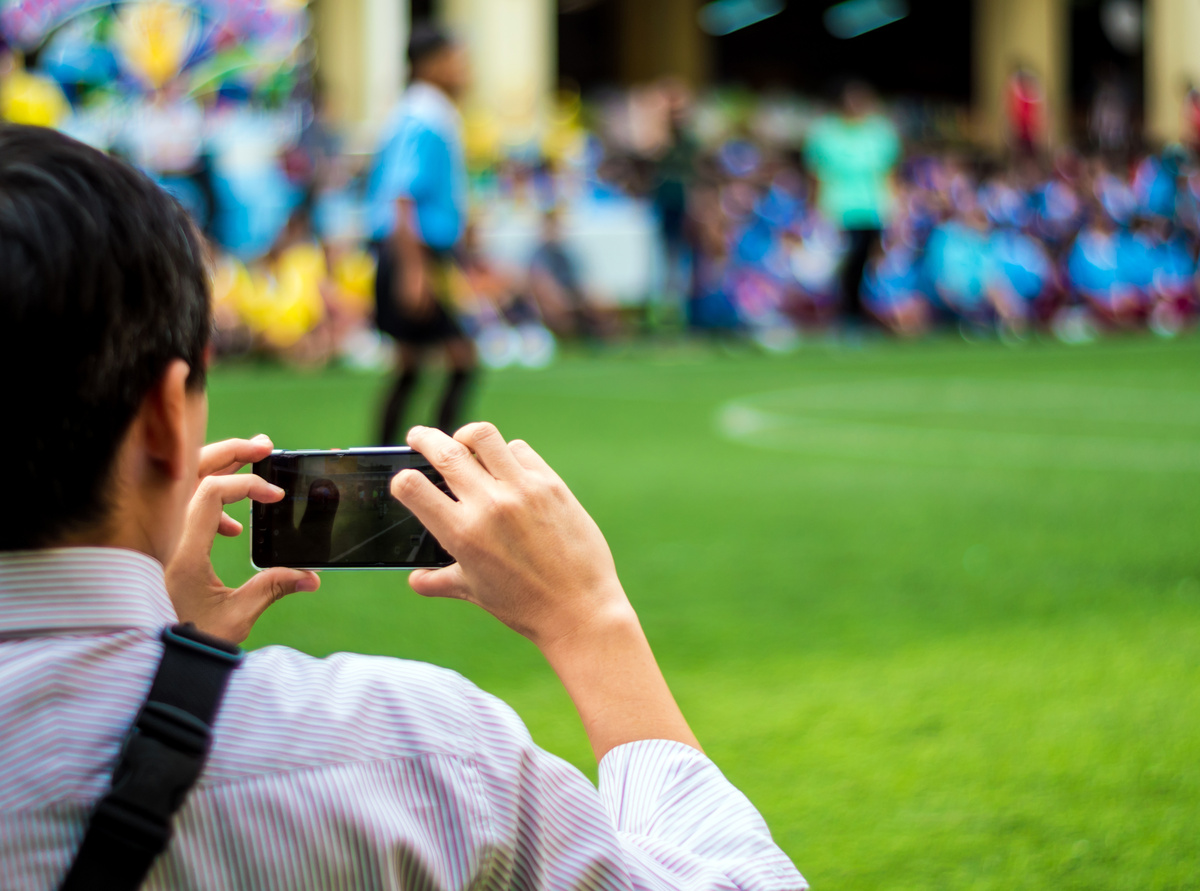 Soccer fan recording football competition with a phone