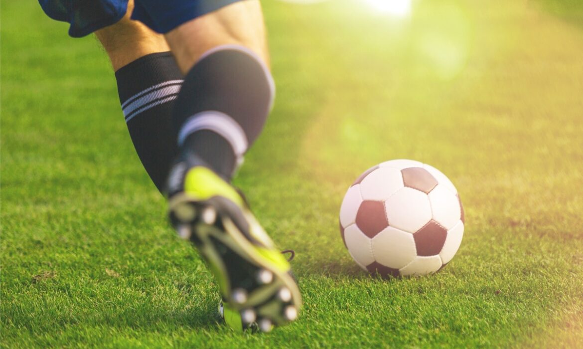 Jogador de futebol correndo na grama