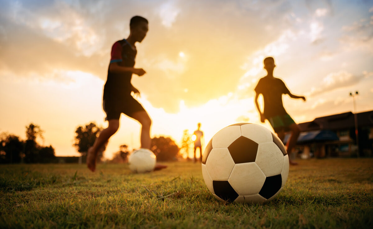 Silhouettes of kids having fun playing soccer football