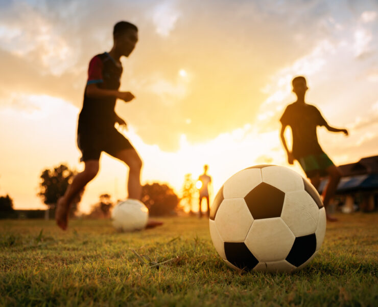 Silhouettes of kids having fun playing soccer football