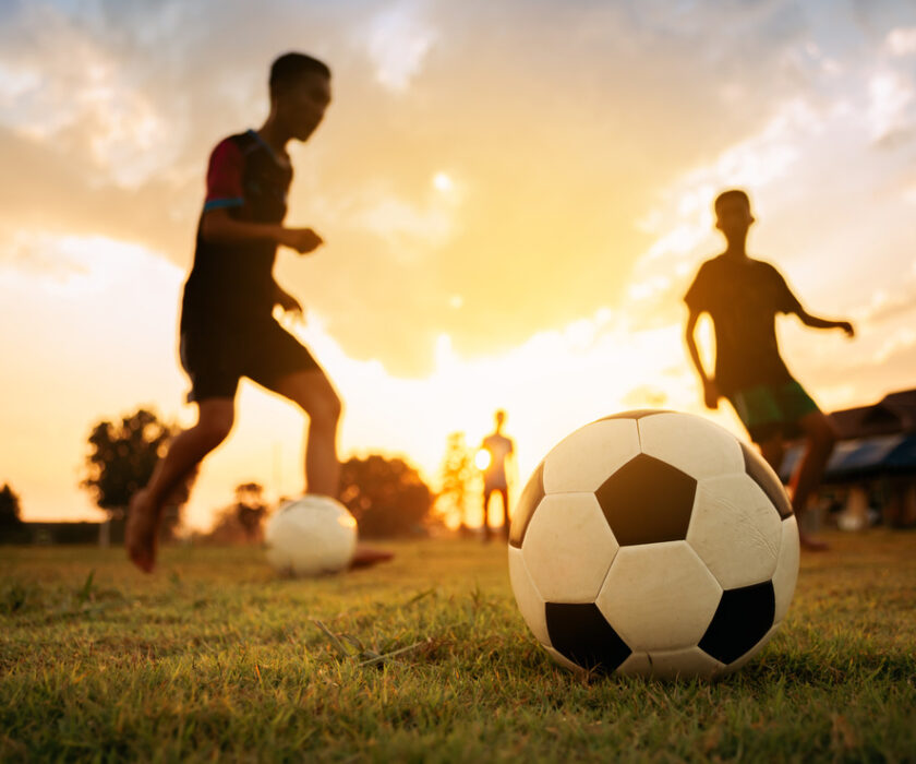 Silhouettes of kids having fun playing soccer football