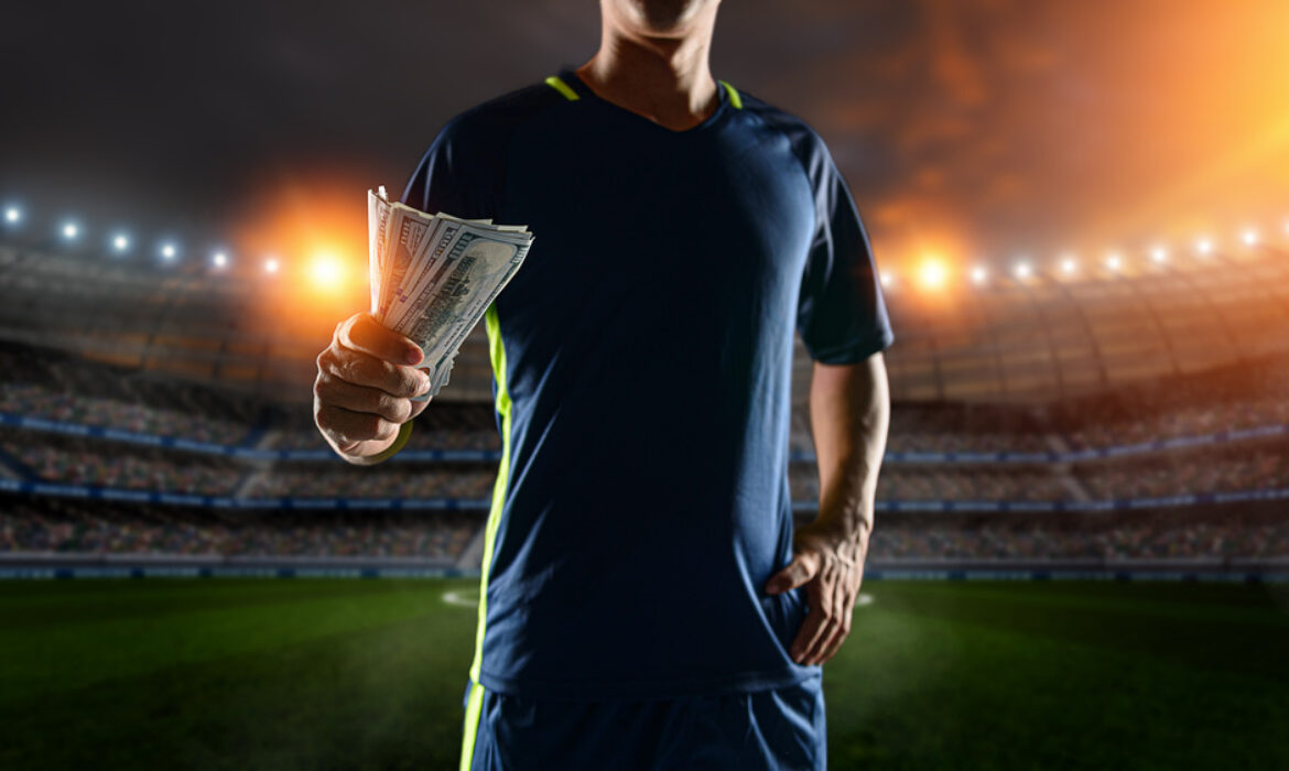 Soccer players holding large amount of bills at Soccer stadium in background