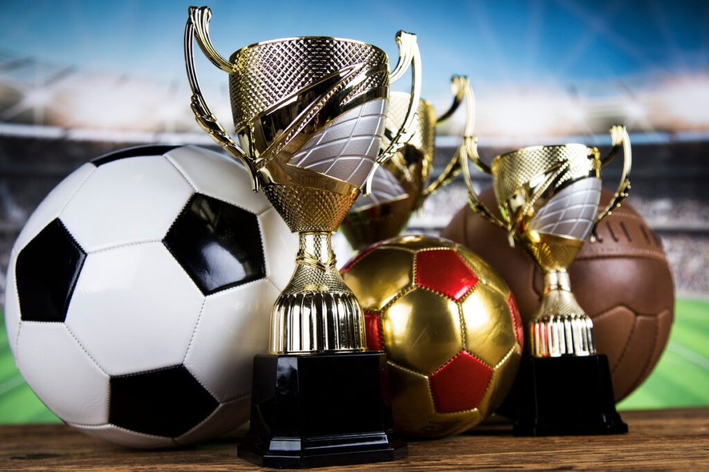 trophies and soccer balls with stadium in the background