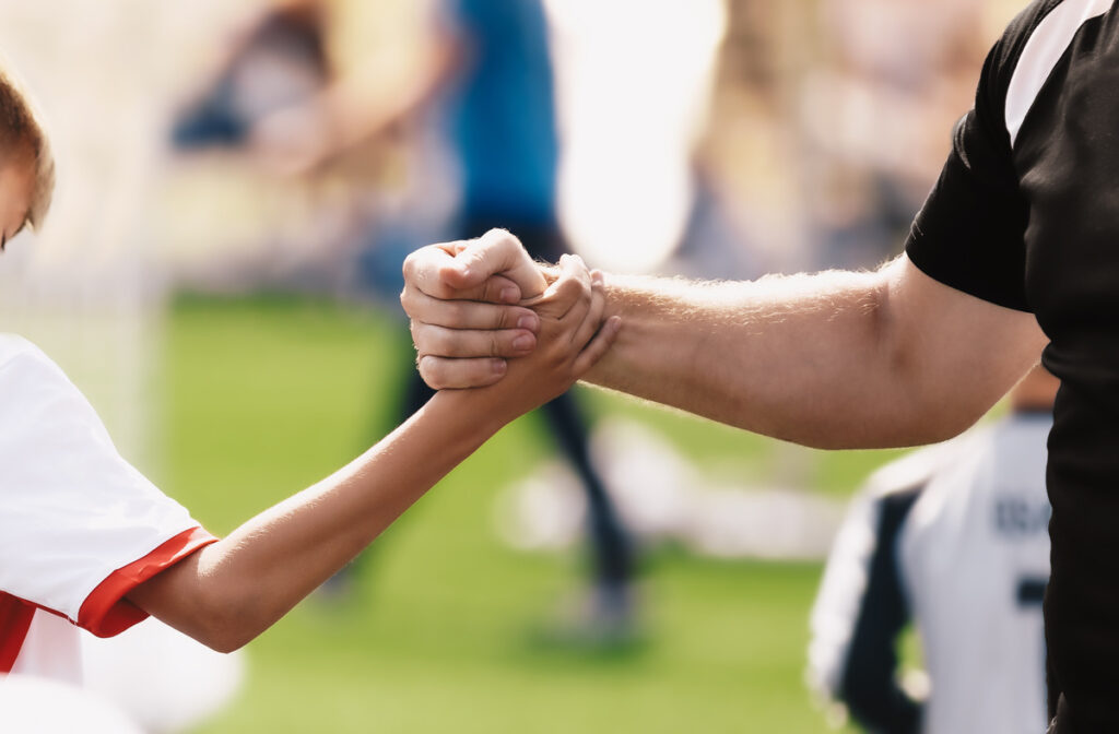 Soccer football kid player shaking hand with the coach