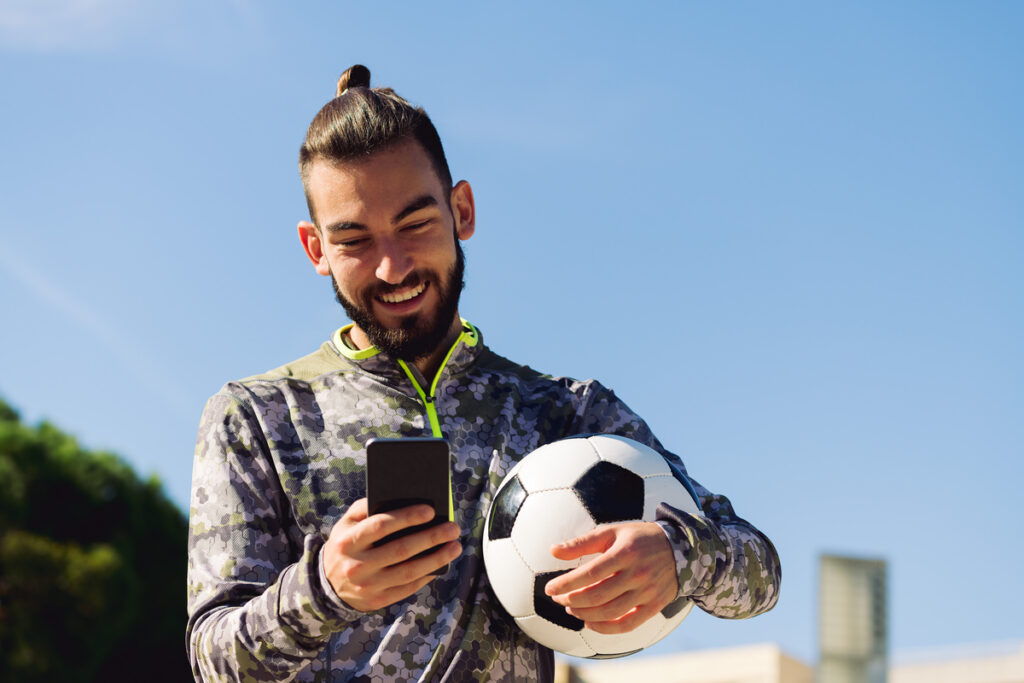 soccer player smiling looking at his mobile phone