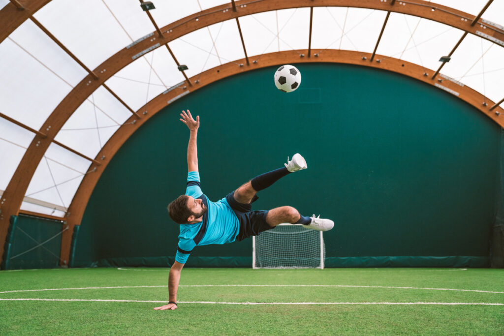 soccer player making tricks with the ball on a artificial grass court indoor