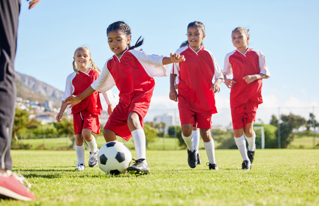 Soccer girl team training playing together on a field