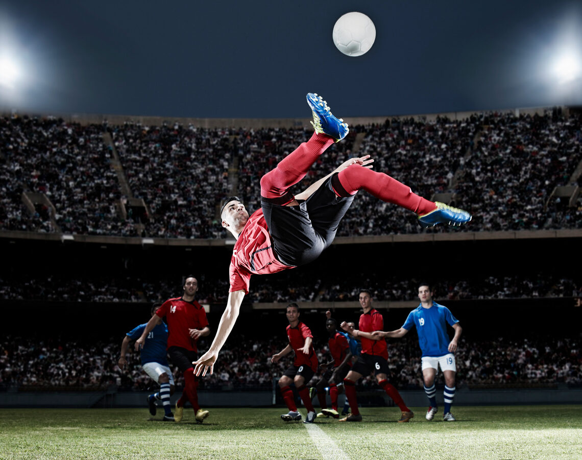 Football player kicking ball mid-air on field