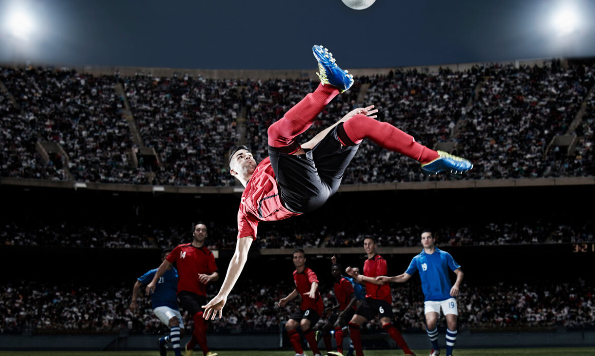 Football player kicking ball mid-air on field