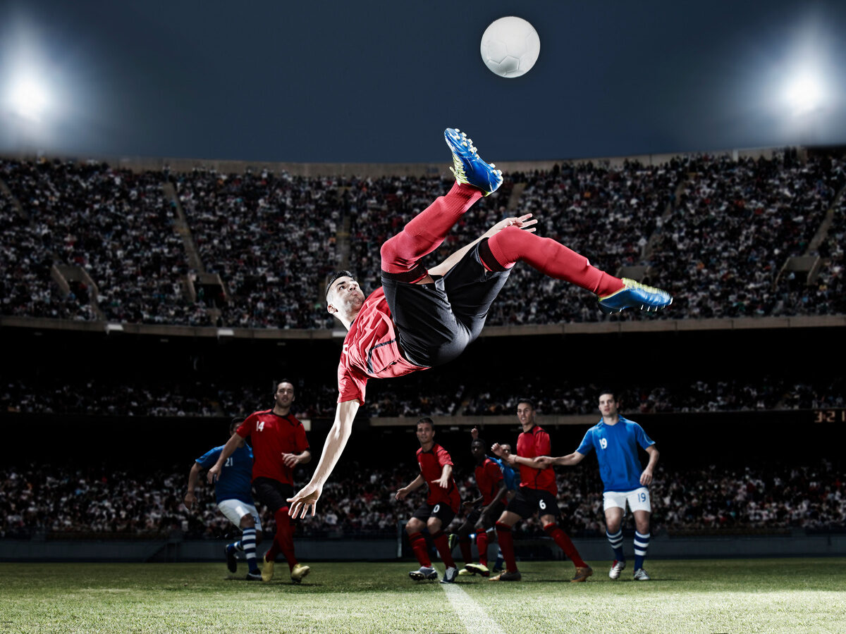 Football player kicking ball mid-air on field