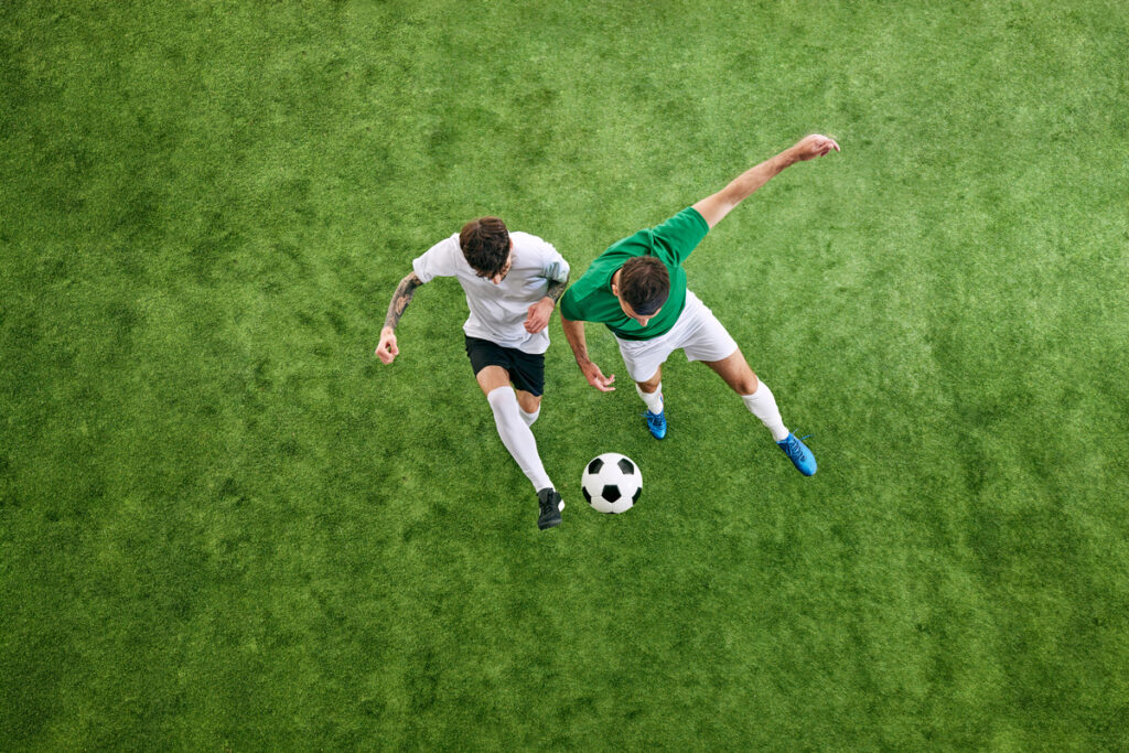 Aerial view. Two male soccer players compete for possession of ball on stadium