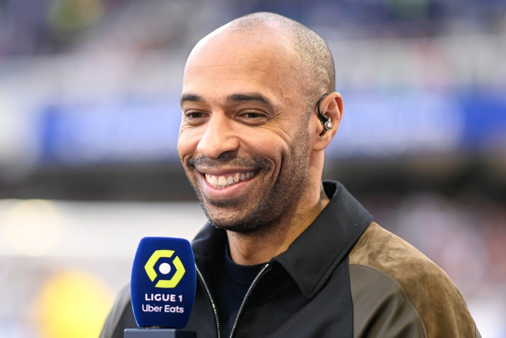 Former footballer Thierry Henry smiling while holding a microphone