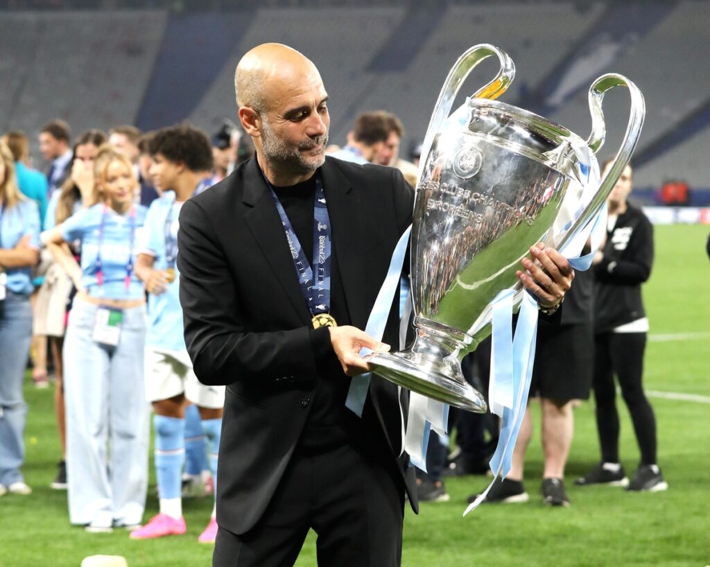 Pep Guardiola posing with the UEFA Champions League trophy