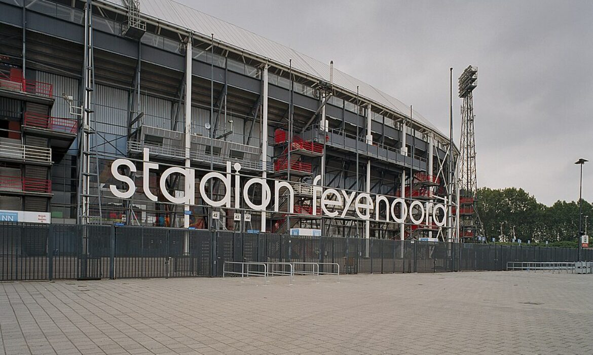 Exterior view of Stadion Feijenoord (De Kuip) in Rotterdam, featuring large white lettering on the facade and a metal framework structure.