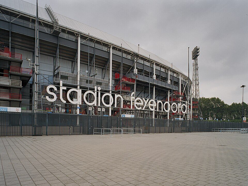Exterior view of Stadion Feijenoord (De Kuip) in Rotterdam, featuring large white lettering on the facade and a metal framework structure.