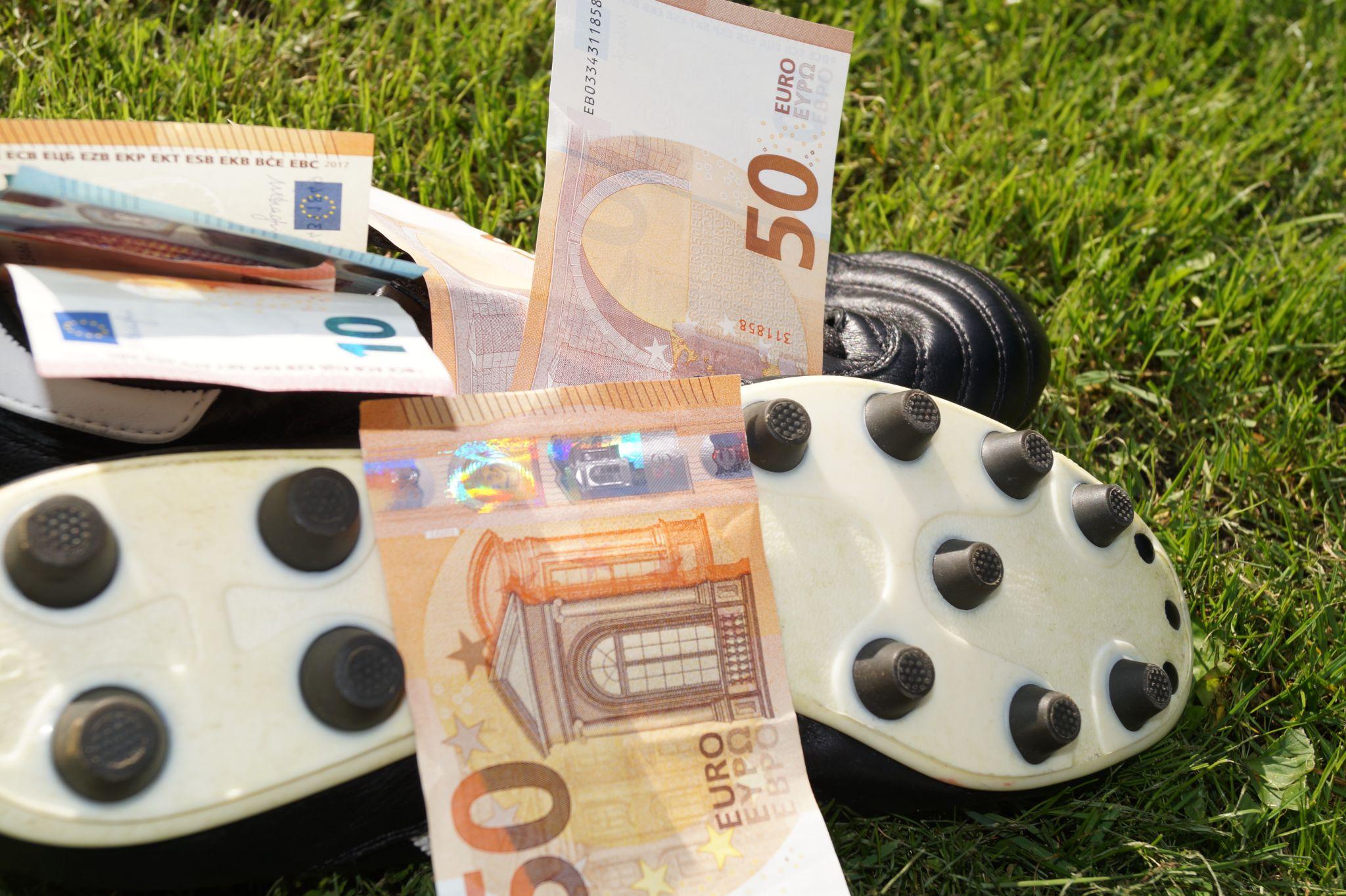 euro bills on top of football shoes